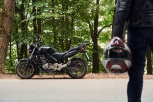 ヘルメットをを持っている人の後ろ姿とバイクの画像